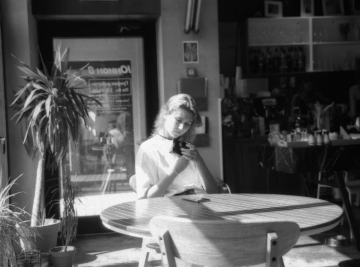 the woman sits at the table and talks on her phone