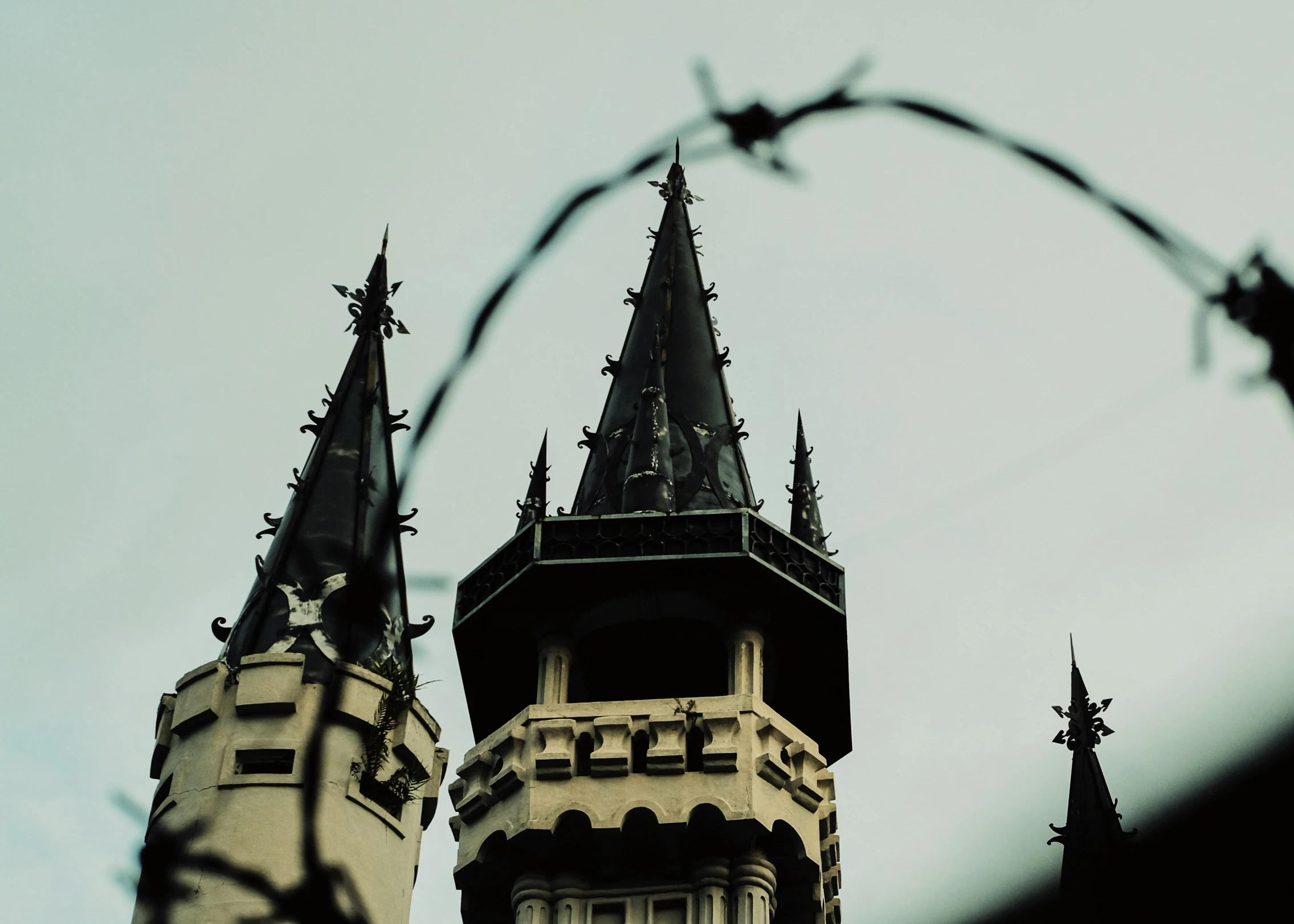 a white clock tower with a cross above it