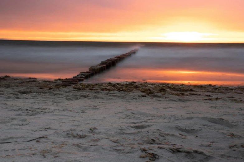 a view of a beach during sunset with the water flowing under it