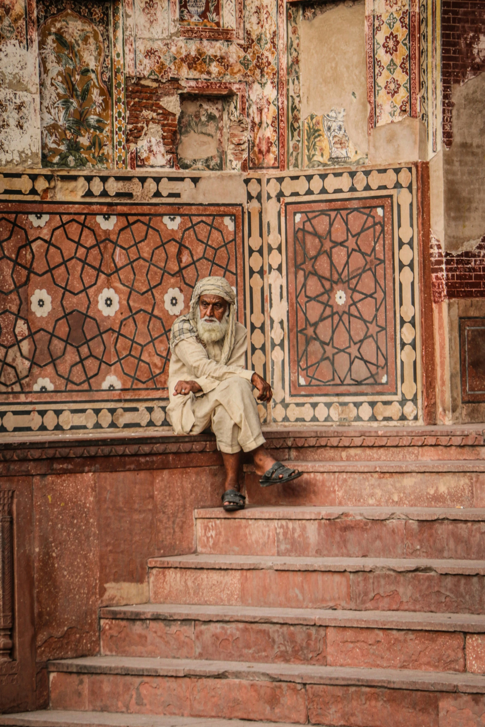 a man sitting on steps wearing sandals and a scarf