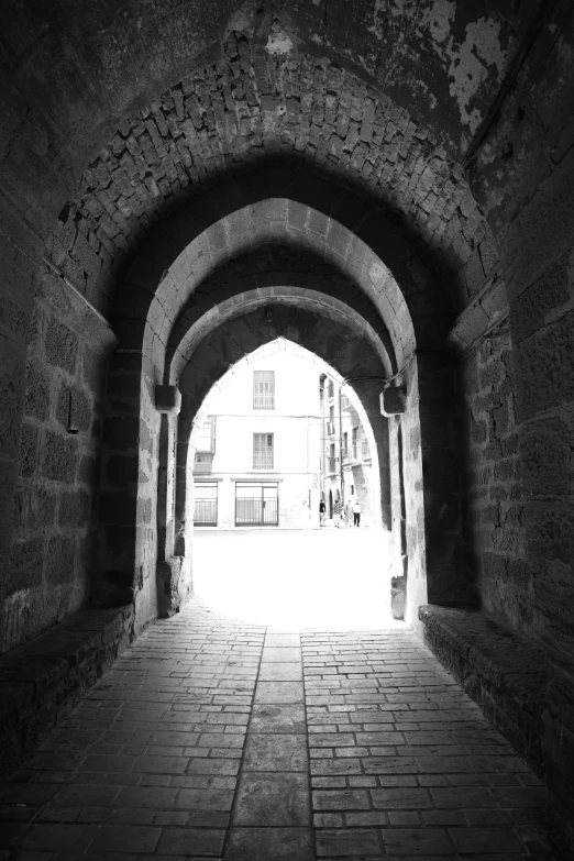 a long brick arch with a bunch of light at the end