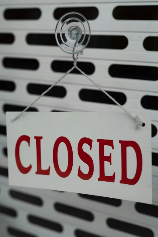 a sign hanging from a metal hook on a white and black wall