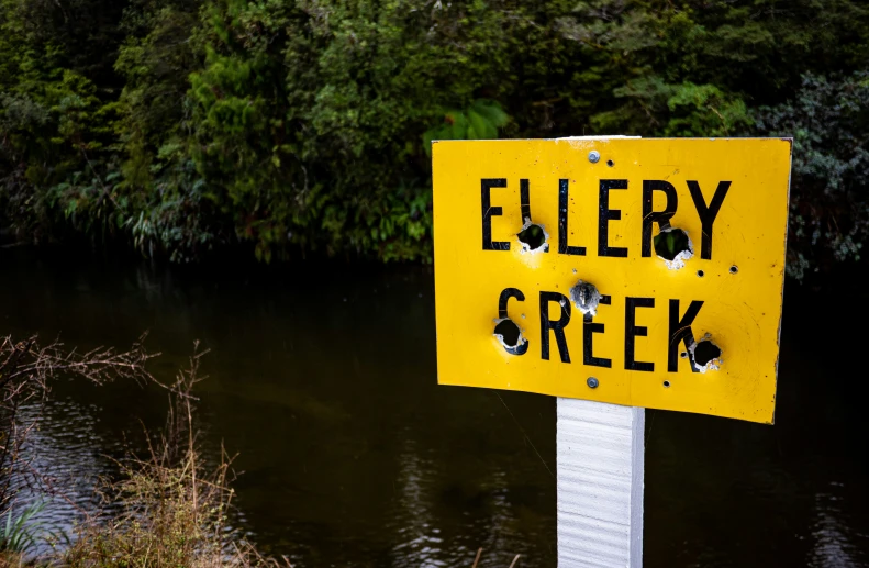 a sign with holes has the words ellen creek