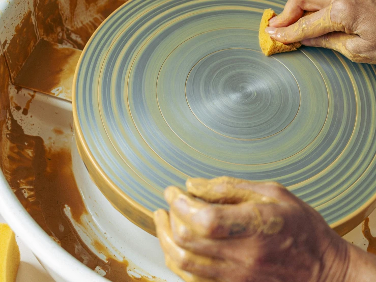 the person has their hands on a blue and white bowl