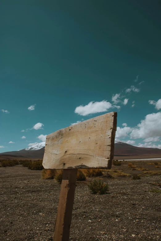 a wooden sign on a dry dirt field