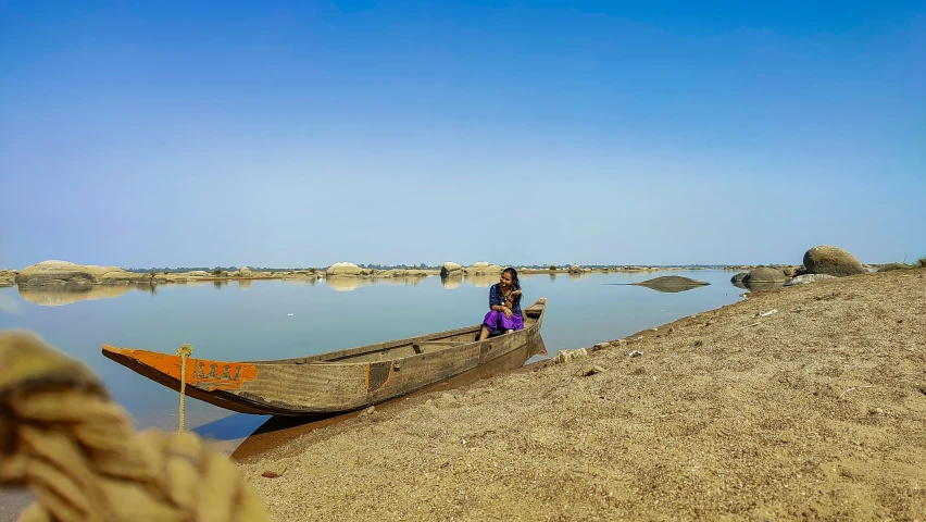 a woman in a dug out canoe by a body of water