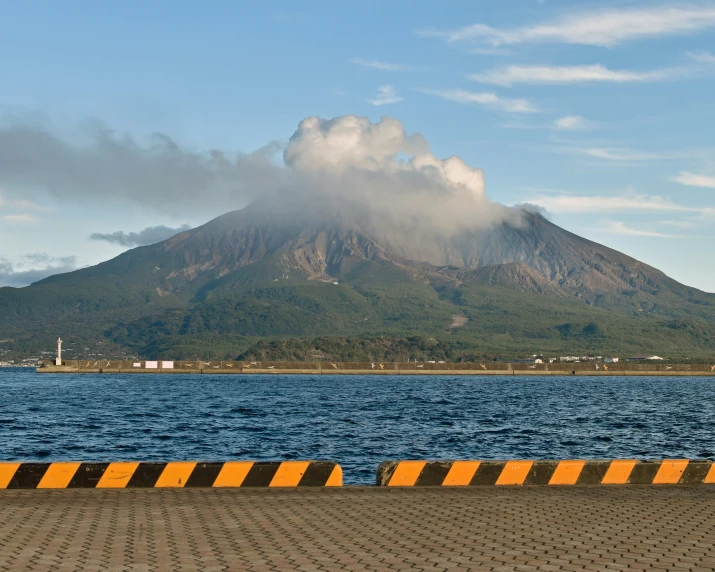 an ocean view of the peak of a mountain, with a fence and traffic area