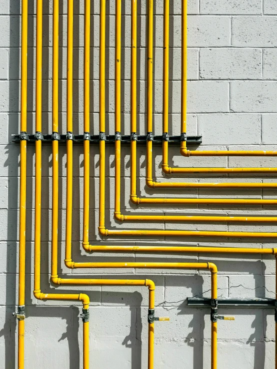 yellow pippes on the wall in front of white brick