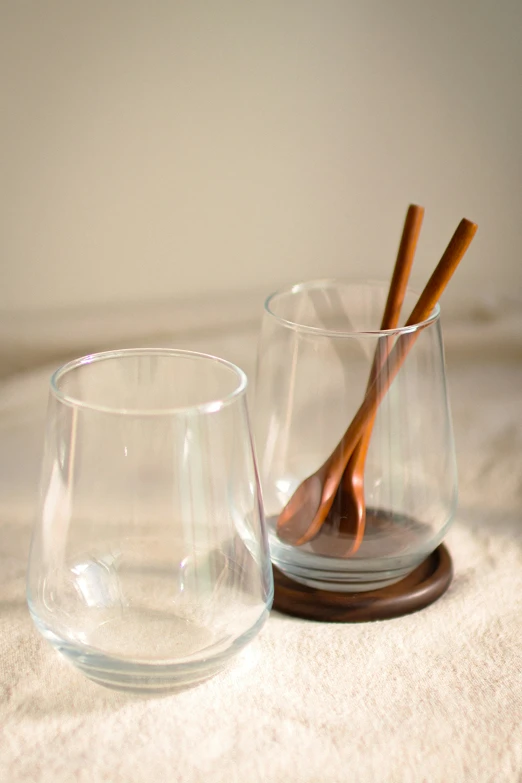 two glass cups, each containing one brown plastic drinking spoon