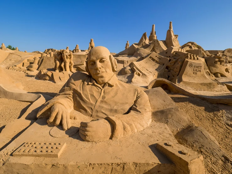 a statue of a man on a beach surrounded by sand