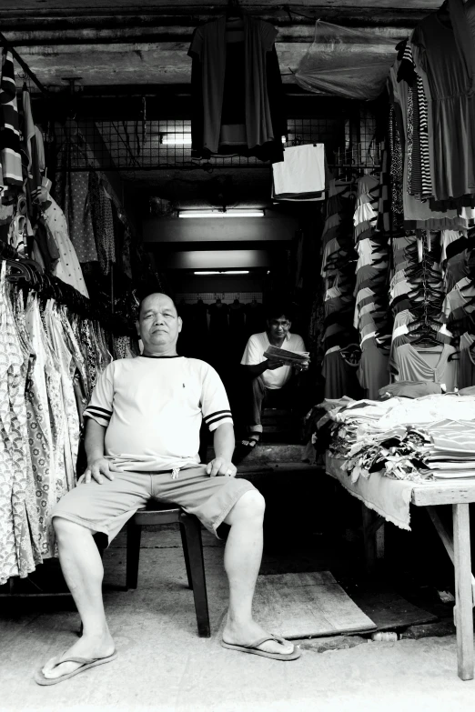 a man is sitting in the doorway to his shop