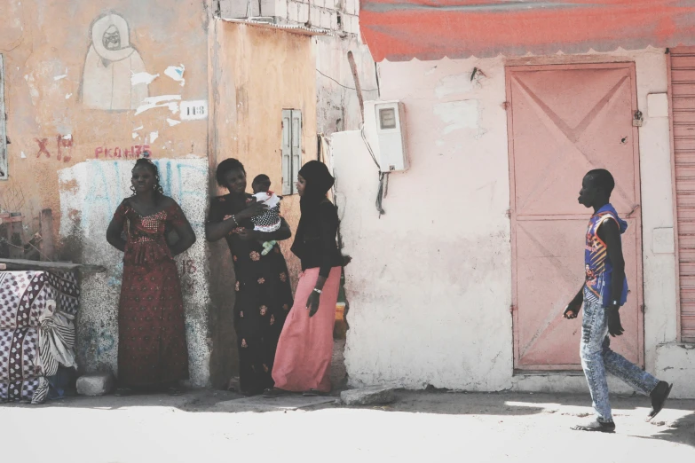 a group of women are walking along the side of a building