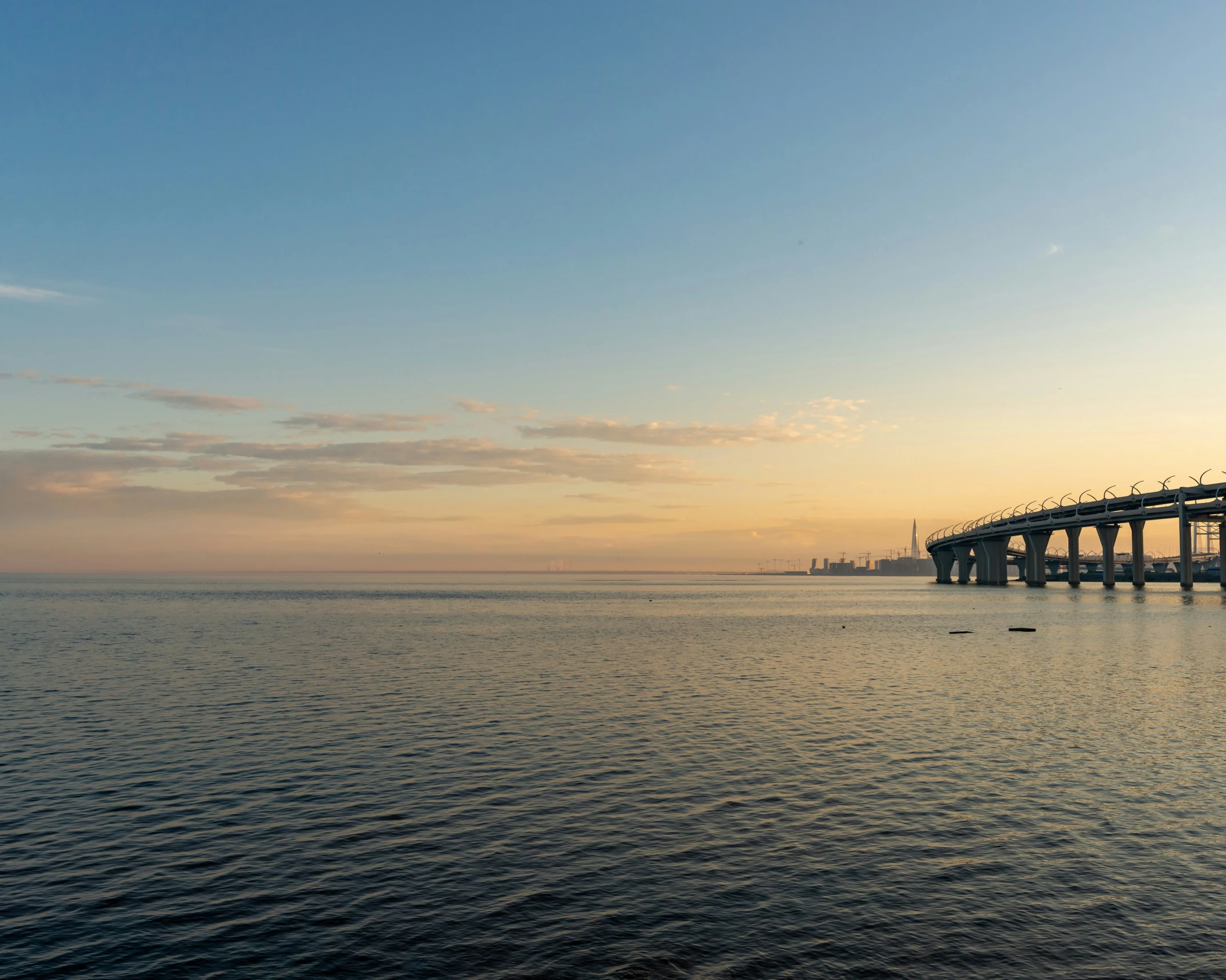 a bridge over water with clouds above