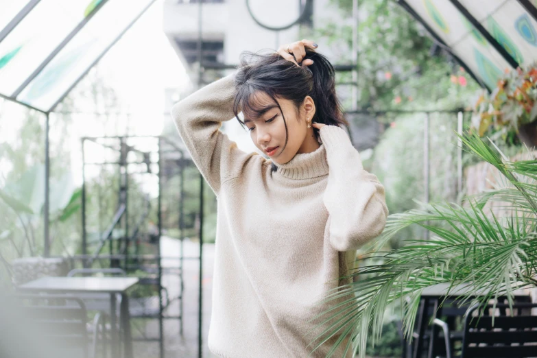 a woman putting her hair up near plants