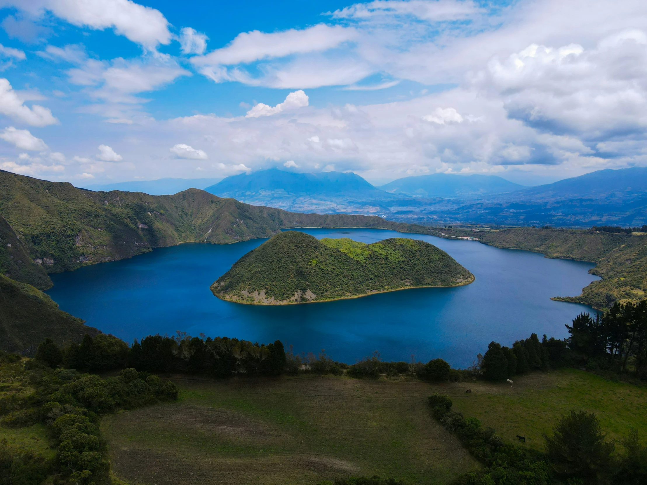 the blue lake is surrounded by green mountains and blue skies