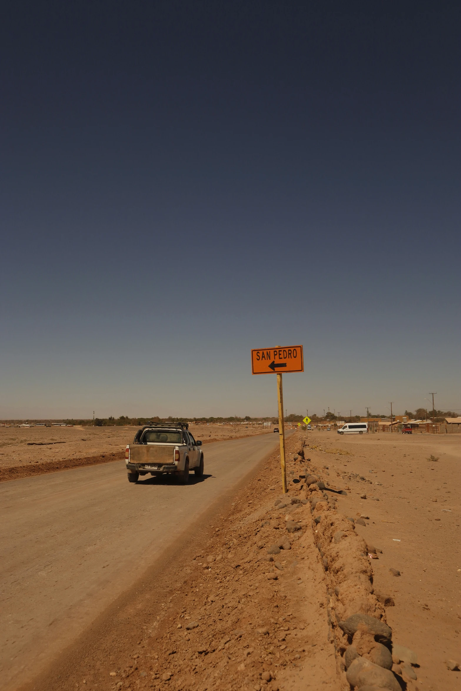 a car is driving along the dirt road with an orange sign that says keep off