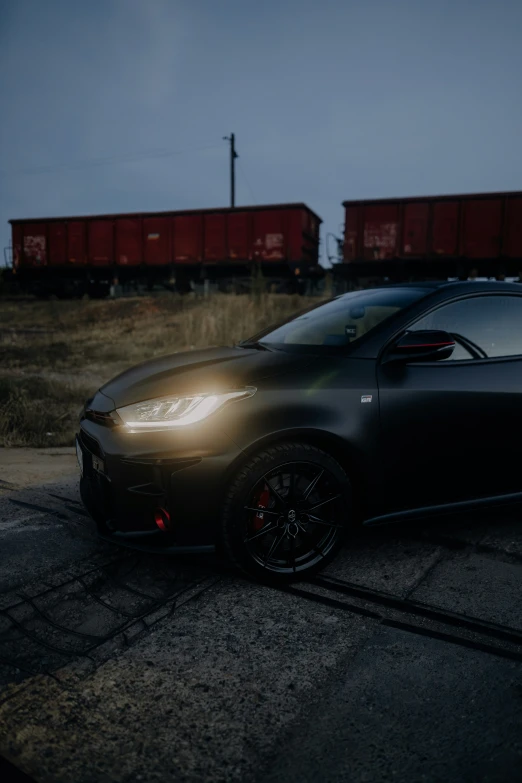 a car parked with its hood down near train tracks