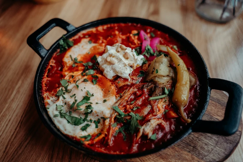 a bowl of food with tomatoes, other things sitting on it