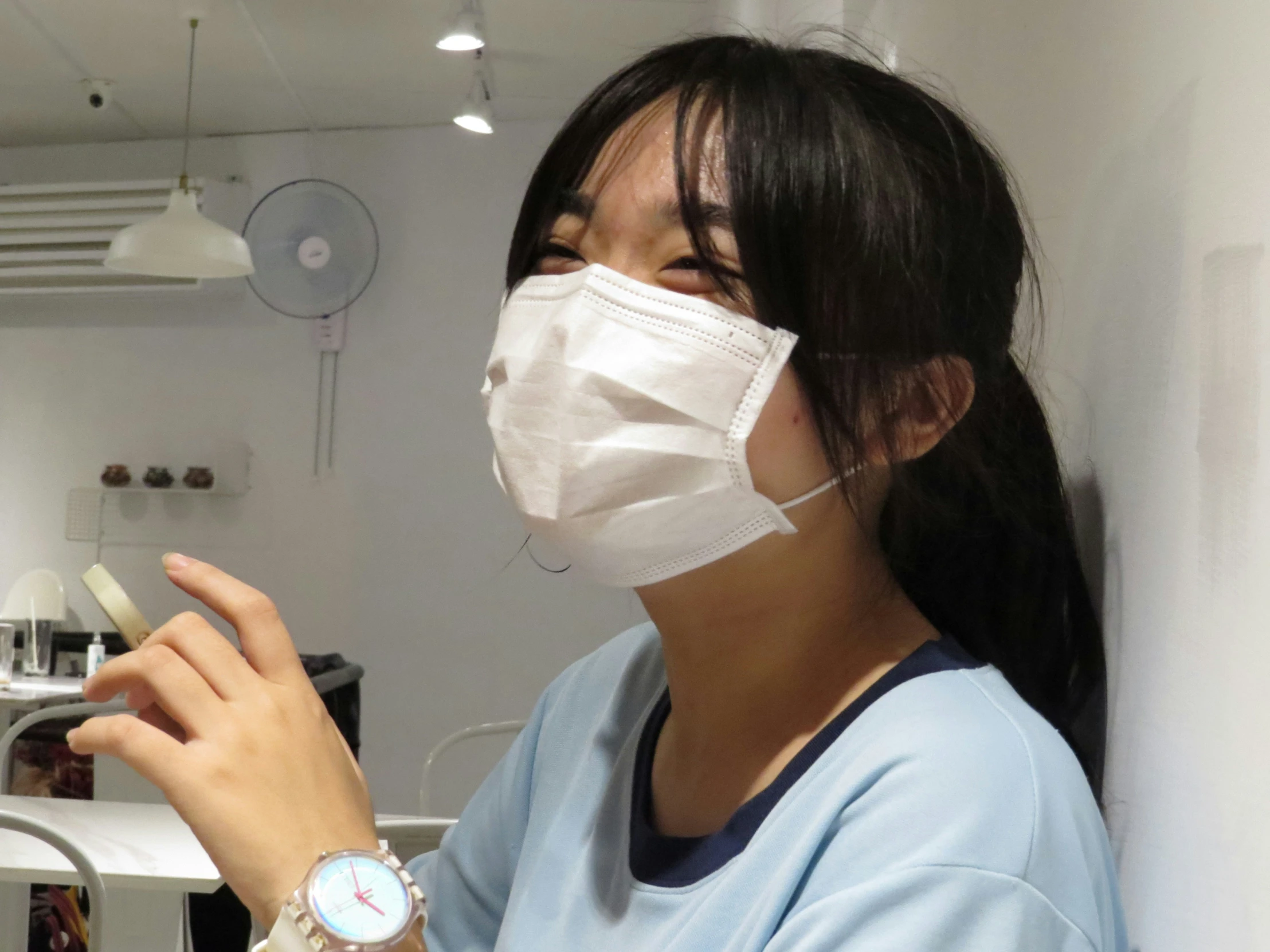 a woman with a mask on is holding a small device