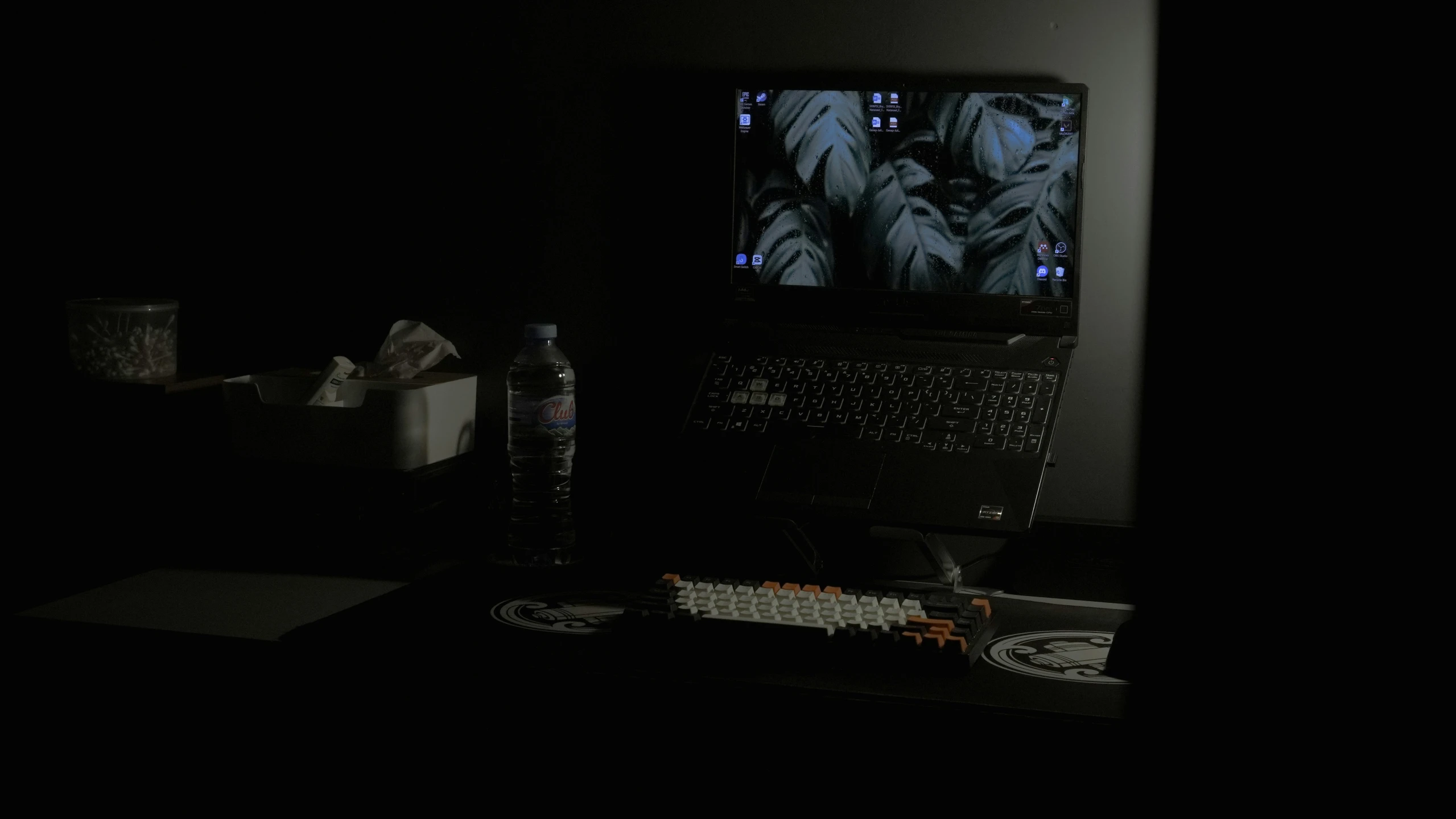 a black room has an open laptop and a soda on a table