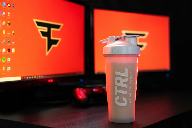 a blender bottle sitting in front of a computer monitor