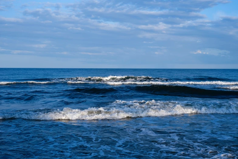 an ocean wave coming toward the shore under a blue sky