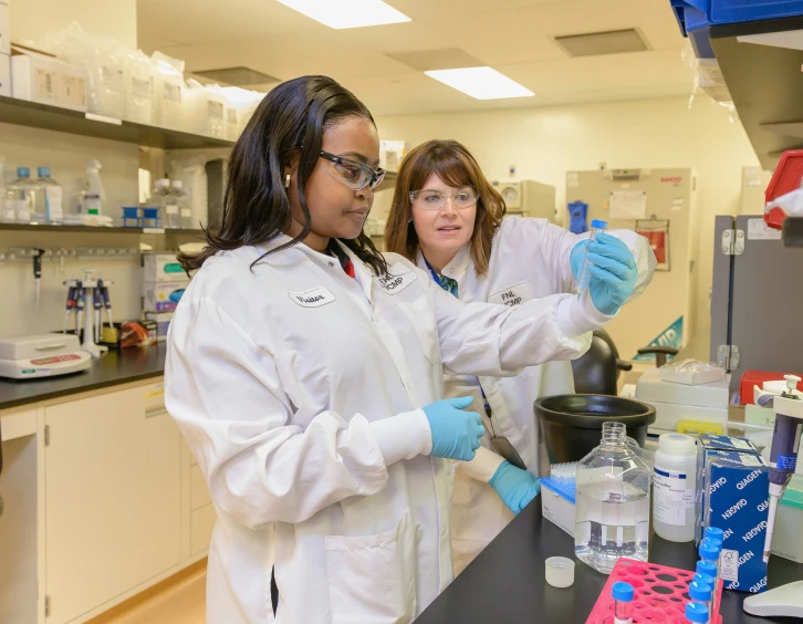 a woman and a young lady in a lab holding laboratory flasks