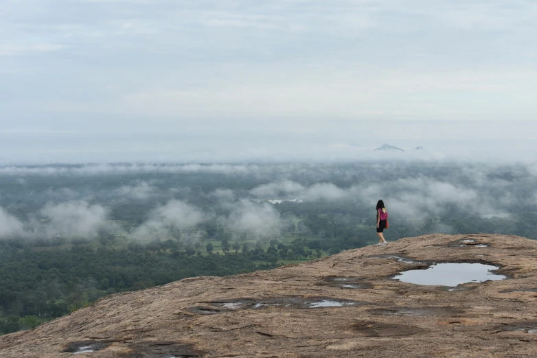 a woman standing on top of a lush green hillside