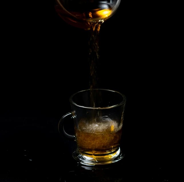 a glass of ice tea being poured into a cup