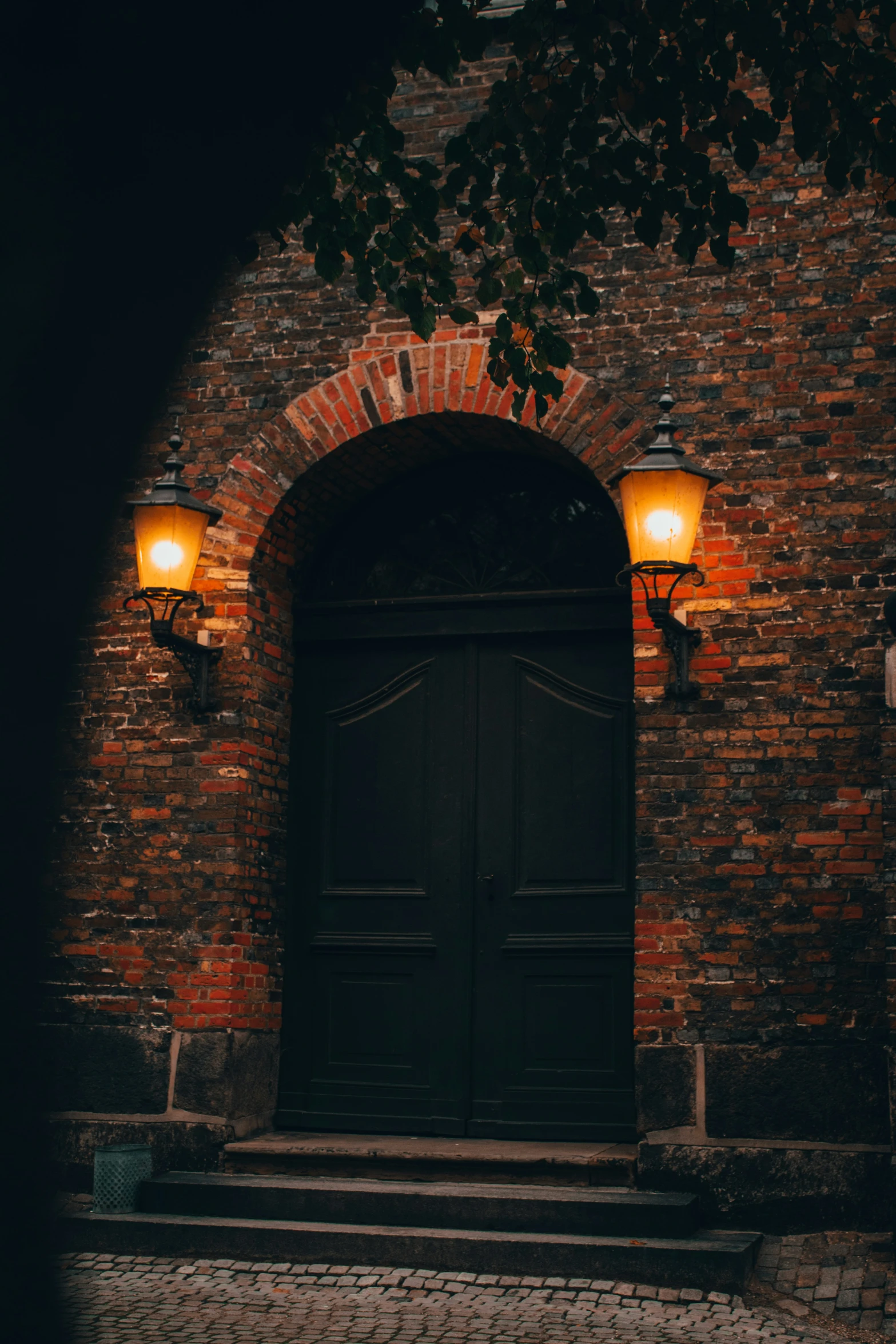 two lights shine on the brick facade of a door