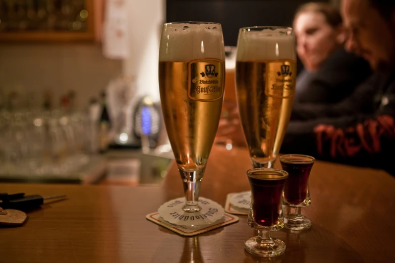 two glass of beer sit on a bar top