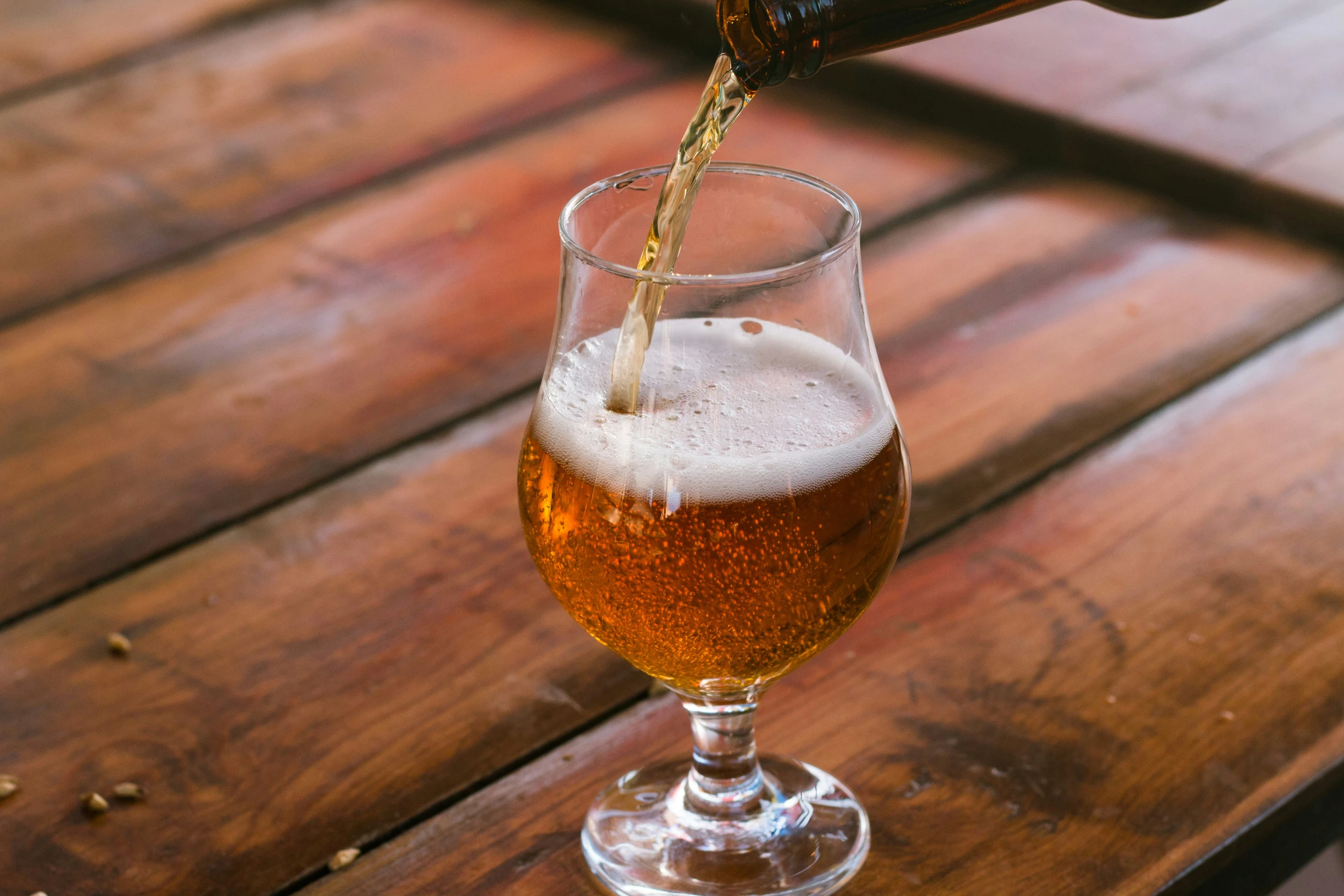 a person pours a beer into a wine glass