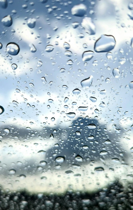 rain on a window with blue cloudy sky