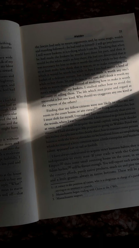 a book opened on the floor with its shadow on it