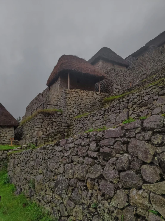 a stone wall next to a lush green hillside