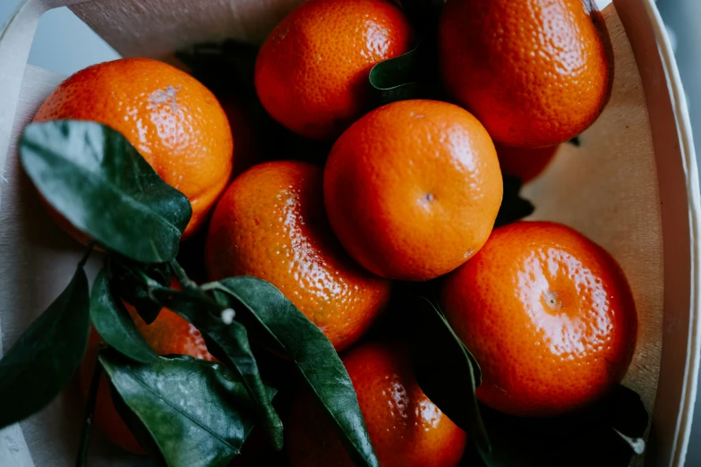 a group of oranges sit together in a bowl