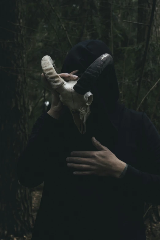 person with a mask holding up a piece of animal bone