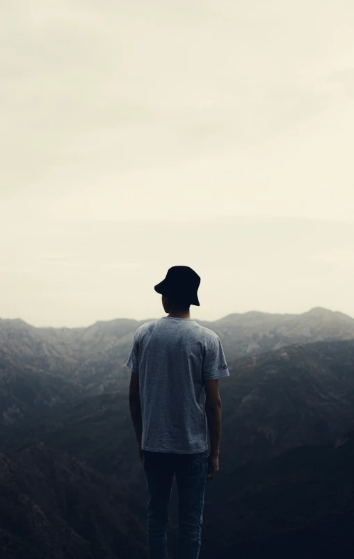 a man in grey shirt standing on cliff top