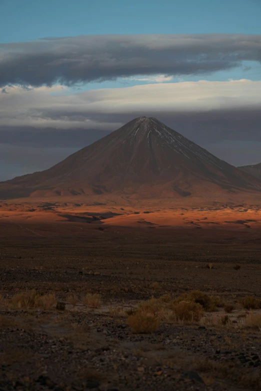 a mountain rises out behind barren plain in the desert