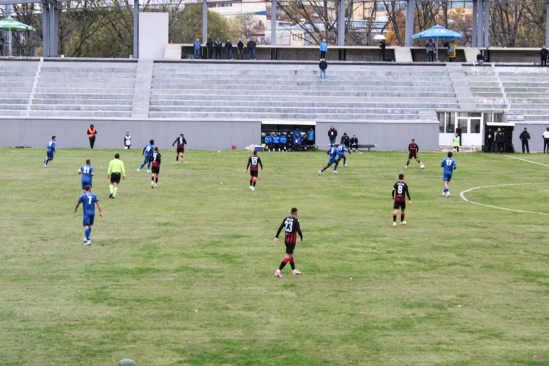 several people playing soccer with grass and water in front of a stadium
