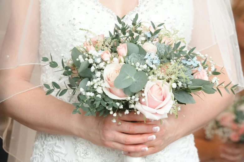 a bride holds a bouquet of flowers and greenery