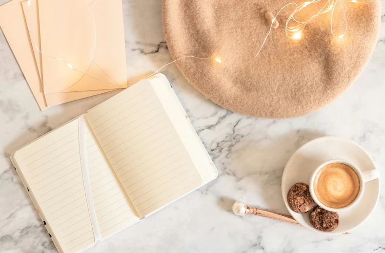 cup, notebook, pen and coffee sitting on a white table