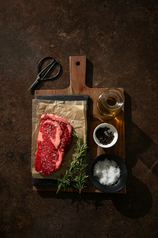 a raw piece of meat with garlic next to it on a wooden  board