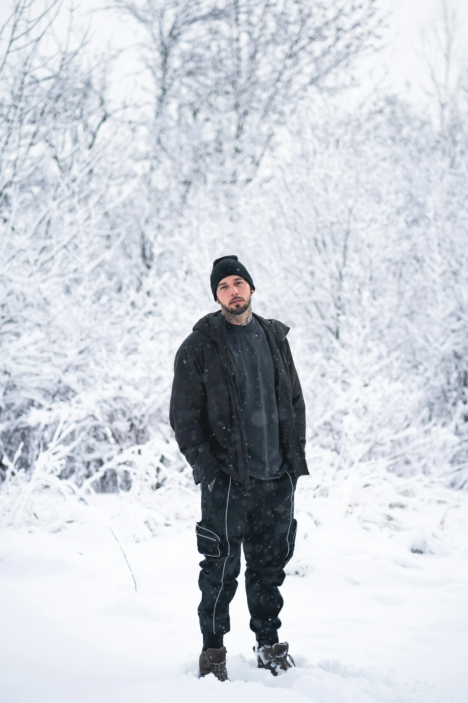 the man poses for a picture in front of a snowy tree