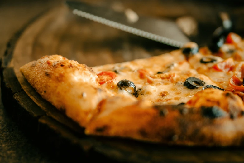 a pizza on a wooden board with a knife in it