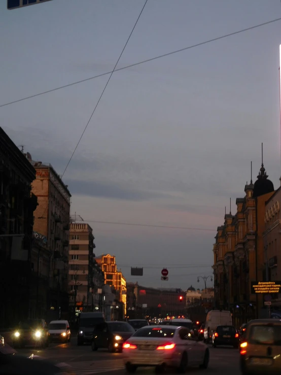 a busy city street with buildings and cars at dusk