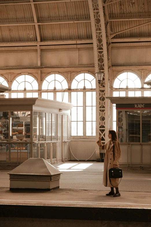 the woman in a long coat is standing next to a statue