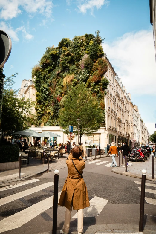 a woman with her back turned taking a picture of a hill in the city