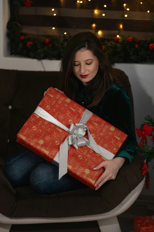 a woman sitting on a chair holding a wrapped present