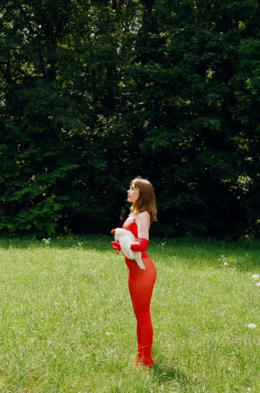 a woman in red dress holding an object in grass